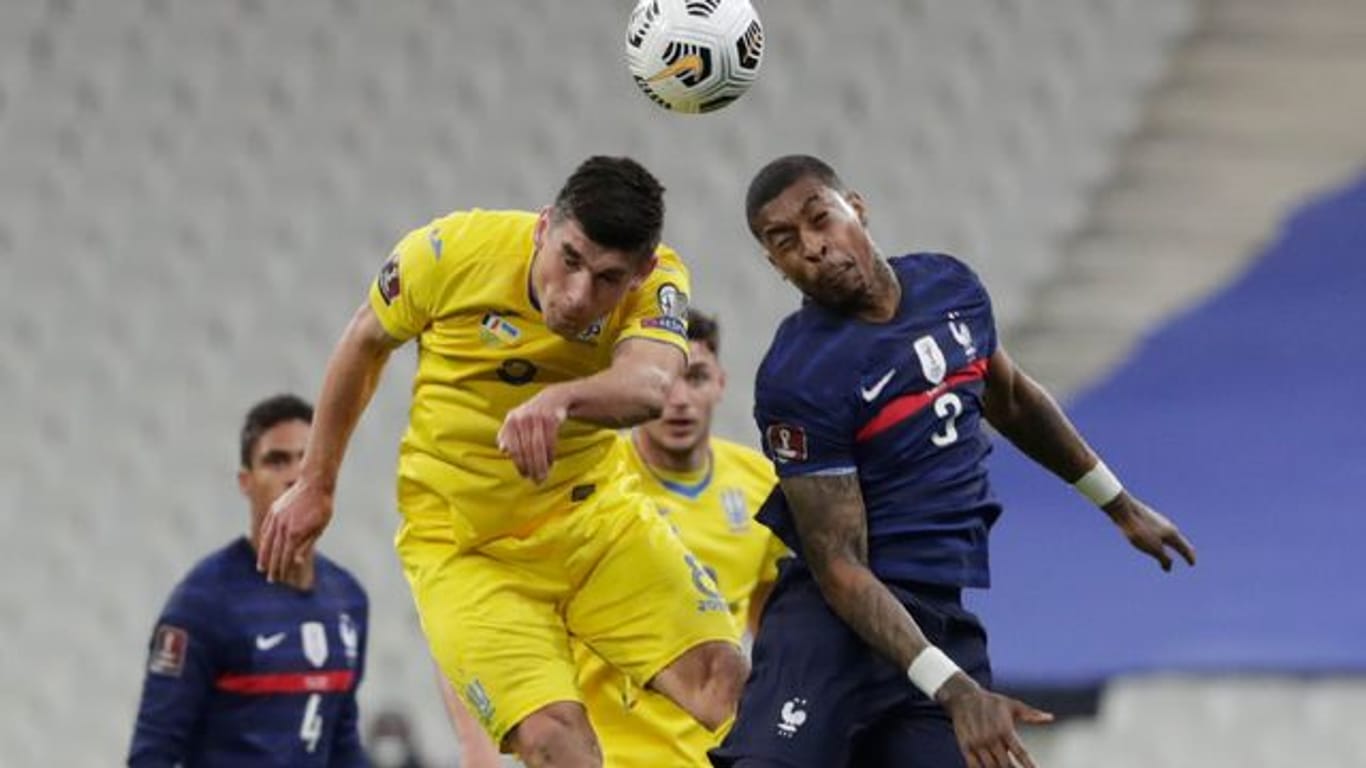 Frankreichs Presnel Kimpembe (r) kämpft mit dem Ukrainer Ruslan Malinowskyj um den Ball.