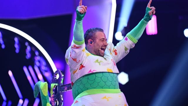 Der Sänger Sasha jubelt im Finale der ProSieben-Show "The Masked Singer" im Kostüm des Dinos. Der Sänger Sasha jubelt im Finale der ProSieben-Show "The Masked Singer" im Kostüm des Dinos.
