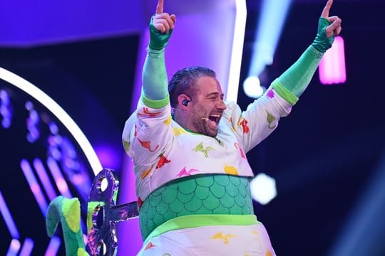 Der Sänger Sasha jubelt im Finale der ProSieben-Show "The Masked Singer" im Kostüm des Dinos.