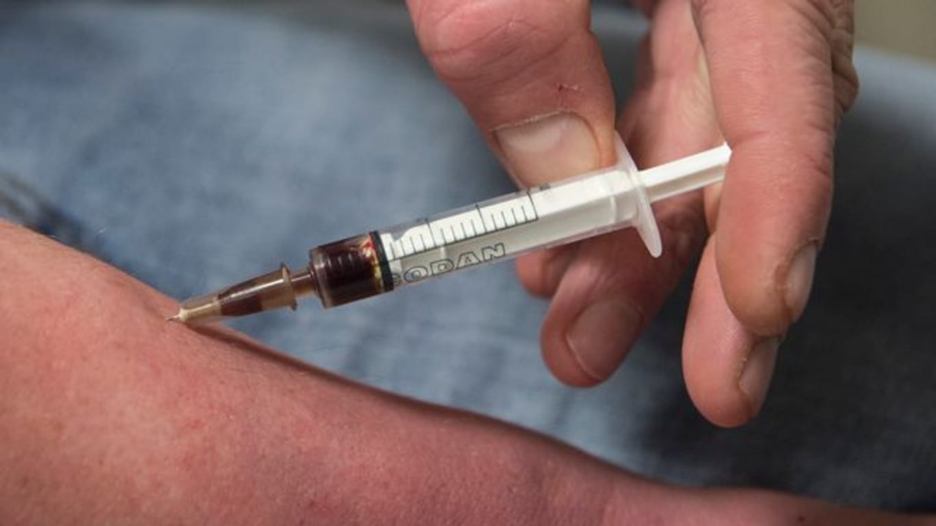 Einen Schuss Heroin spritzt sich ein Suchtkranker im Druckraum in den Unterarm.