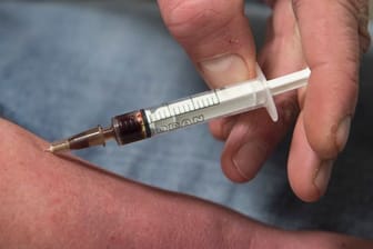 Einen Schuss Heroin spritzt sich ein Suchtkranker im Druckraum in den Unterarm.