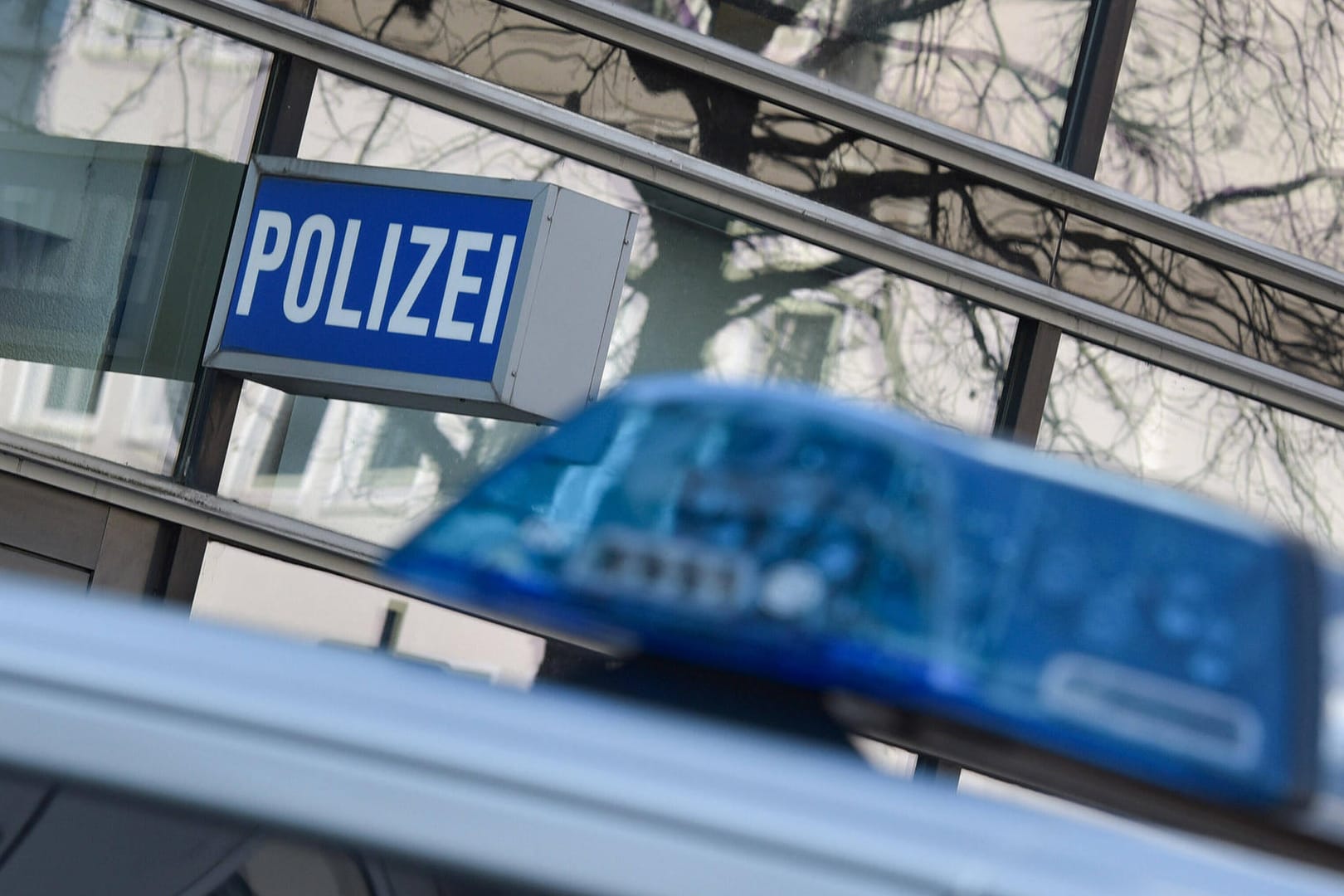 Ein Polizeiauto steht unter dem Schild an einer Wache (Symbolbild): Nachdem er gewalttätig gegenüber seiner Frau geworden ist, wurde ein Mann in Polizeigewahrsam genommen.