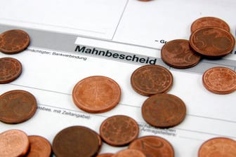 Centstücke liegen auf einem Mahnbescheid (Symybolbild): Die Agentur für Arbeit fordete einen Cent von der Düsseldorferin.