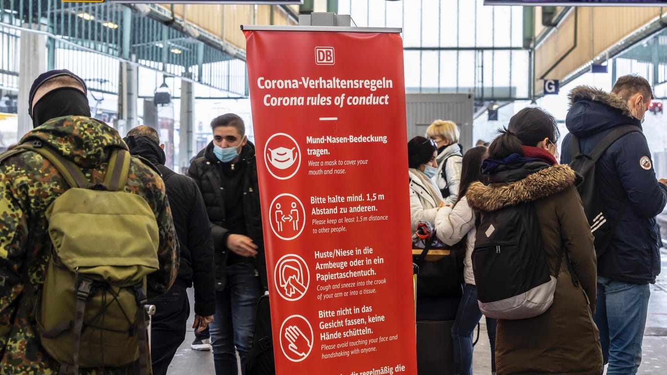 Reisende am Hauptbahnhof Stuttgart: Ein Schild verweist auf die Corona-Verhaltensregeln.