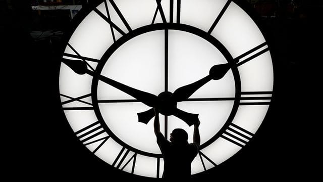 Ein Techniker bewegt die Uhrzeiger einer 500 kg schweren Uhr.