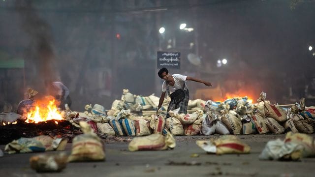 Ein Demonstrant stapelt Säcke auf einer Straße als Barrikade während eines Protestes in Yangon. Ein Demonstrant stapelt Säcke auf einer Straße als Barrikade während eines Protestes in Yangon.