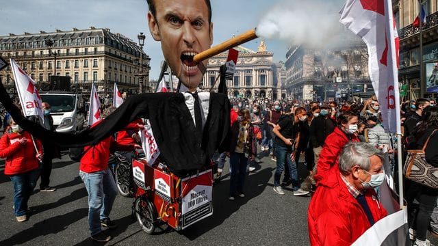 Demonstranten ziehen mit einem Zigarre rauchenden Abbild des französischen Präsidenten Macron durch Paris. Demonstranten ziehen mit einem Zigarre rauchenden Abbild des französischen Präsidenten Macron durch Paris.