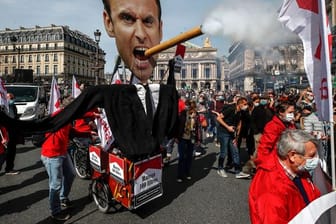 Demonstranten ziehen mit einem Zigarre rauchenden Abbild des französischen Präsidenten Macron durch Paris.