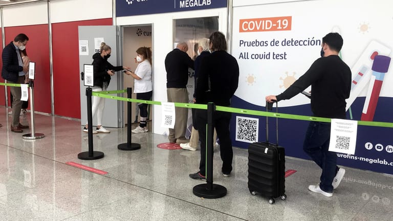 People wait in queue outside a COVID-19 test site at Son Sant Joan airport in Palma de Mallorca