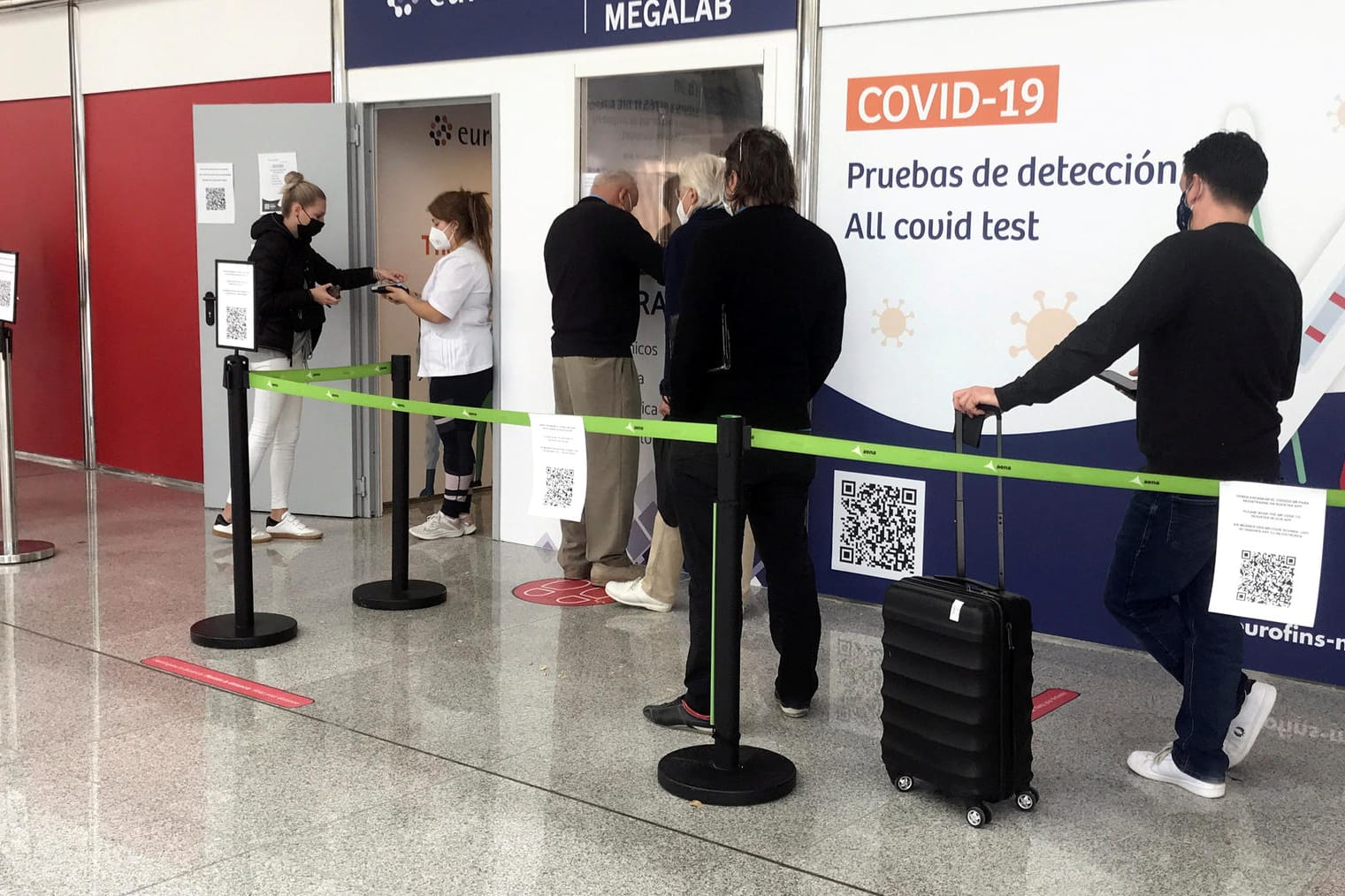 People wait in queue outside a COVID-19 test site at Son Sant Joan airport in Palma de Mallorca