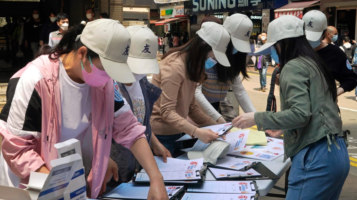 Pro-China-Mitarbeiterinnen sammeln Unterschriften von Anwohnern an einem Stand zur Unterstützung eines Vorschlags zur Änderung der Wahlregeln für Hongkong: Nun kann Peking de facto die Kandidaten für Wahlen in Hongkong auswählen.