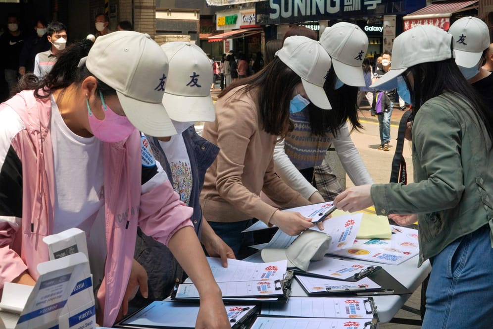 Pro-China-Mitarbeiterinnen sammeln Unterschriften von Anwohnern an einem Stand zur Unterstützung eines Vorschlags zur Änderung der Wahlregeln für Hongkong: Nun kann Peking de facto die Kandidaten für Wahlen in Hongkong auswählen.