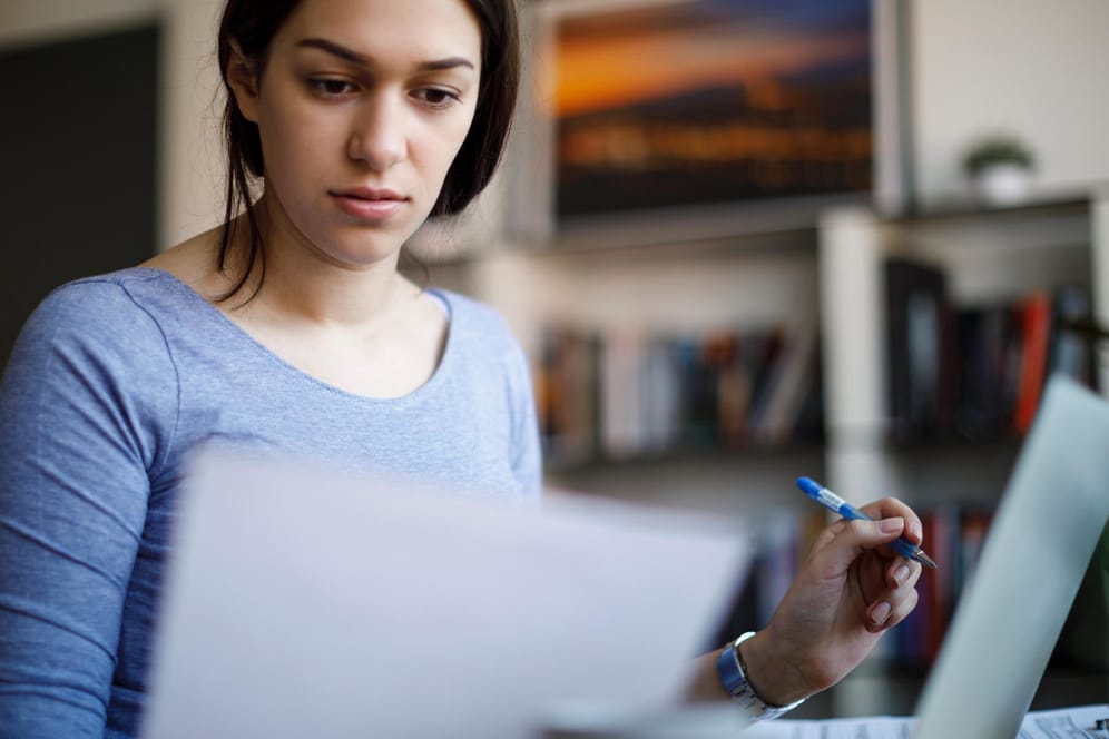 Eine Frau blickt auf ein Dokument (Symbolbild): Wer Lohnersatzleistungen bezieht, dem könnte eine Steuernachzahlung drohen.
