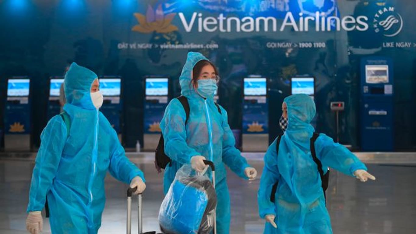 Passagiere in voller Schutzkleidung gegen das Coronavirus gehen durch den Flughafen Hanoi.