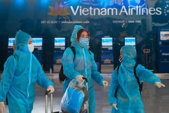 Passagiere in voller Schutzkleidung gegen das Coronavirus gehen durch den Flughafen Hanoi.