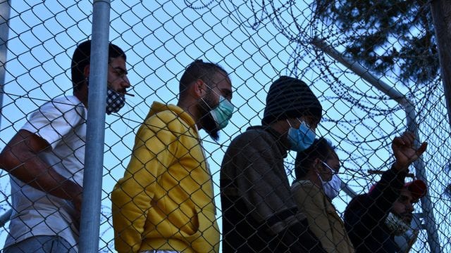 Migranten in einem Flüchtlingscamp am Hafen von Vathy auf der Insel Samos beobachten den Besuch der EU-Innenkommissarin Johansson.