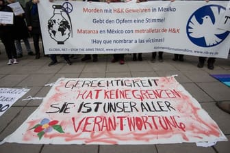 Demonstranten stehen vor der Urteilsverkündung im Prozess gegen ehemalige Mitarbeiter von Heckler und Koch mit einem Transparent vor dem Landgericht Stuttgart.
