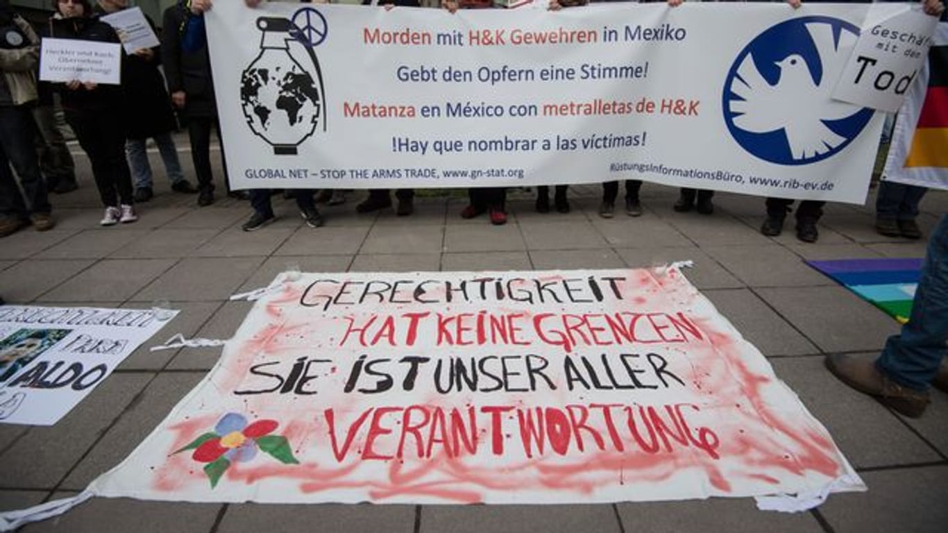 Demonstranten stehen vor der Urteilsverkündung im Prozess gegen ehemalige Mitarbeiter von Heckler und Koch mit einem Transparent vor dem Landgericht Stuttgart.