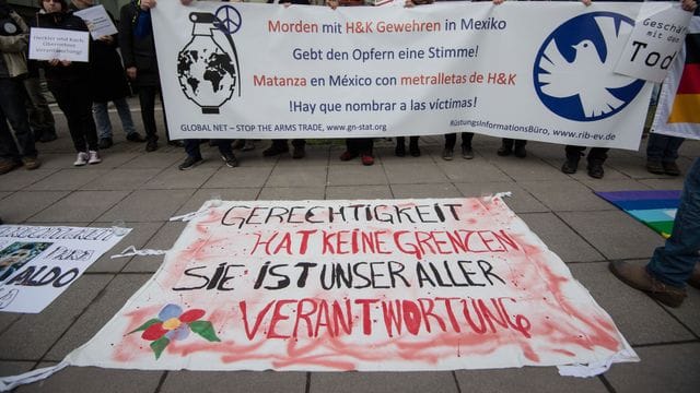 Demonstranten stehen vor der Urteilsverkündung im Prozess gegen ehemalige Mitarbeiter von Heckler und Koch mit einem Transparent vor dem Landgericht Stuttgart. Demonstranten stehen vor der Urteilsverkündung im Prozess gegen ehemalige Mitarbeiter von Heckler und Koch mit einem Transparent vor dem Landgericht Stuttgart.