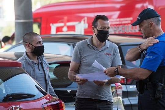 Zwei Männer sprechen am Grenzübergang mit einem Grenzbeamten und zeigen Dokumente vor.