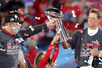 Das Objekt der Begierde in der Hand: Superstar Tom Brady (r.) präsentiert die weltbekannte Vince Lombardi Trophy für das beste Team der NFL.