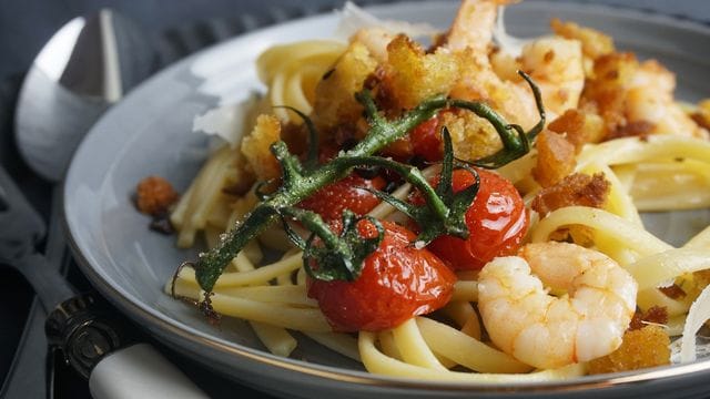 Chilibrösel geben dem Garnelen-Linguine-Teller Crunch, der Strunk der Cherrytomaten einen Farbtupfer.