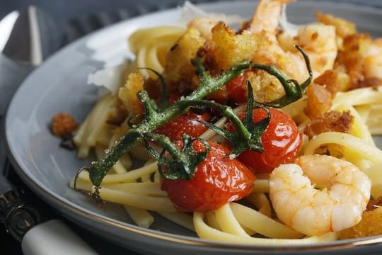 Chilibrösel geben dem Garnelen-Linguine-Teller Crunch, der Strunk der Cherrytomaten einen Farbtupfer.