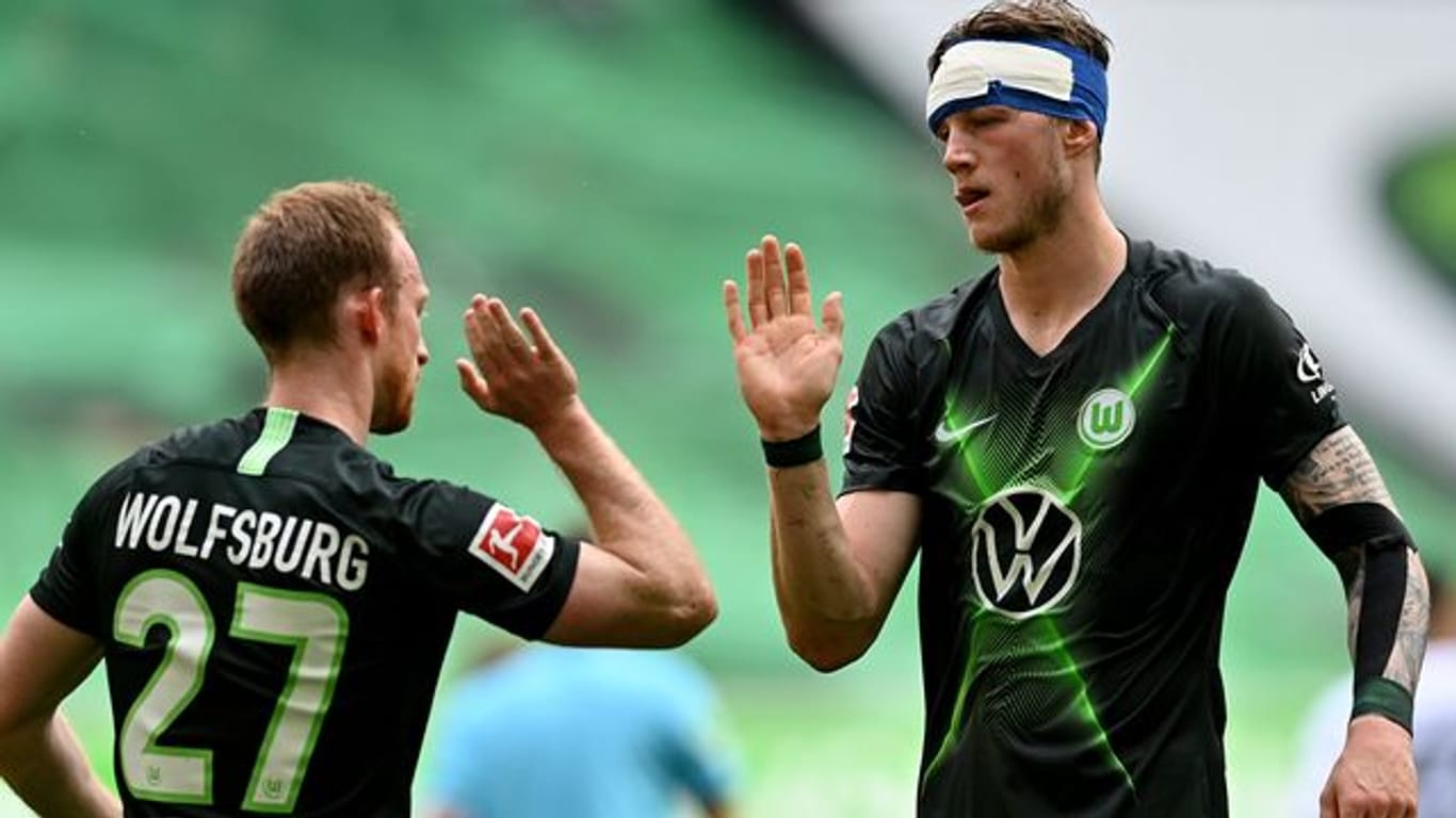 Wolfsburgs Stürmer Weghorst (r), der einen Verband am Kopf trägt, bejubelt einen Treffer mit Mannschaftskamerad Arnold.