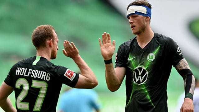 Wolfsburgs Stürmer Weghorst (r), der einen Verband am Kopf trägt, bejubelt einen Treffer mit Mannschaftskamerad Arnold. Wolfsburgs Stürmer Weghorst (r), der einen Verband am Kopf trägt, bejubelt einen Treffer mit Mannschaftskamerad Arnold.