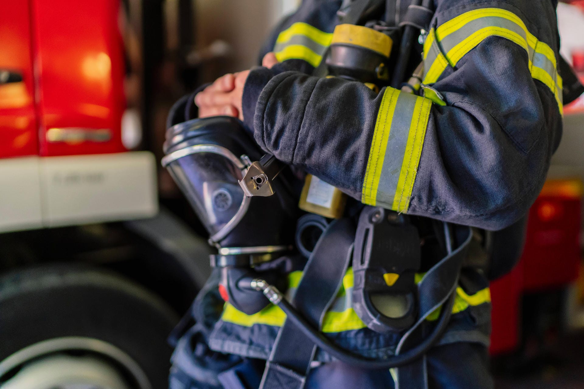 Ein Mitarbeiter der Feuerwehr trägt eine Uniform und eine Gasmaske (Symbolbild): Wegen der großen Explosionsgefahr musste der Bereich um den Brand gesperrt werden.