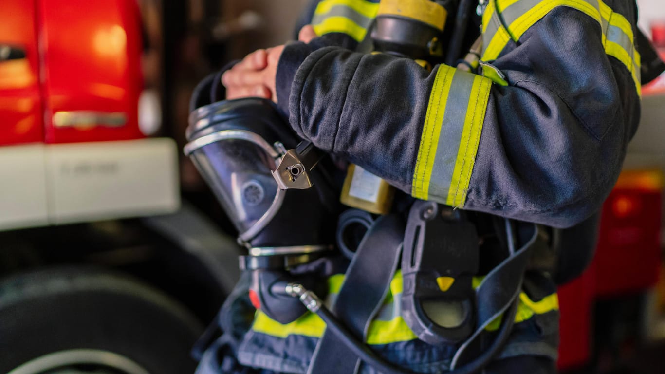 Ein Mitarbeiter der Feuerwehr trägt eine Uniform und eine Gasmaske (Symbolbild): Wegen der großen Explosionsgefahr musste der Bereich um den Brand gesperrt werden.