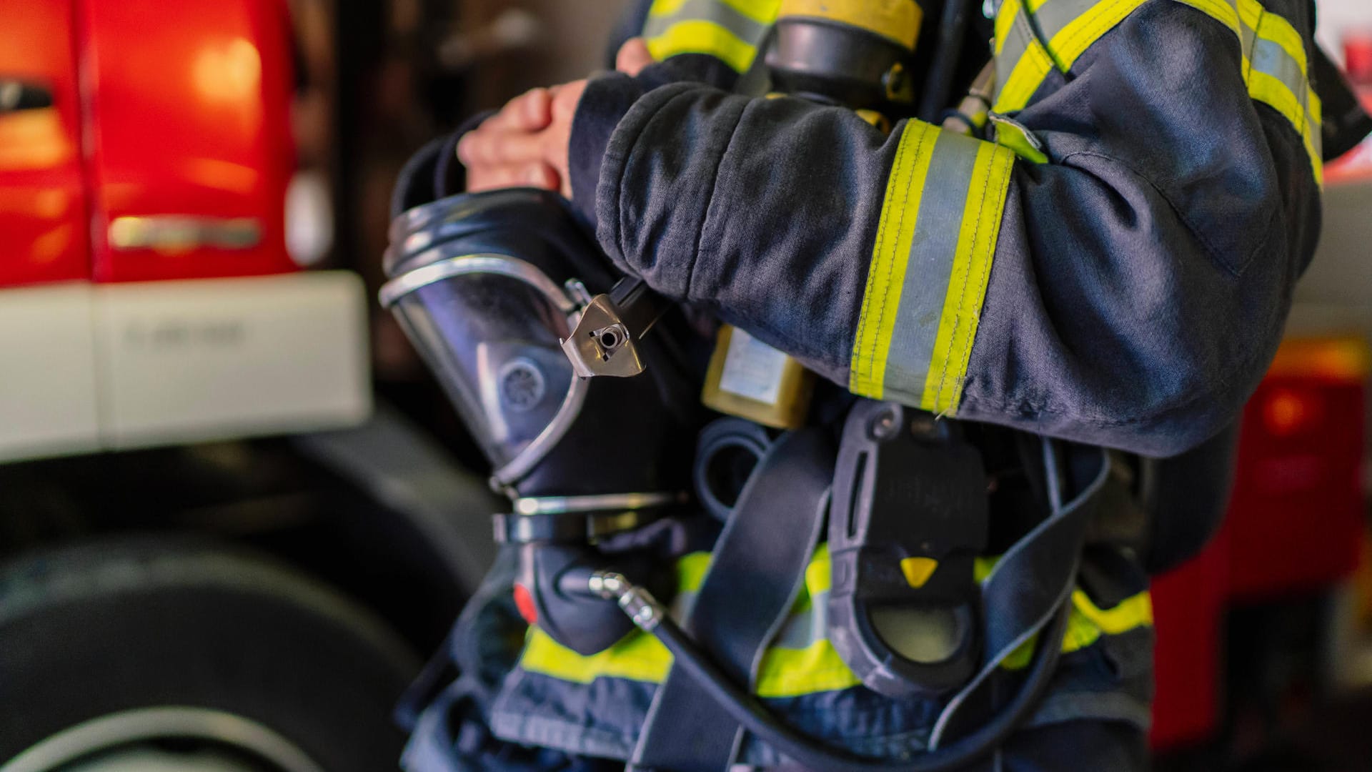 Ein Mitarbeiter der Feuerwehr trägt eine Uniform und eine Gasmaske (Symbolbild): Wegen der großen Explosionsgefahr musste der Bereich um den Brand gesperrt werden.