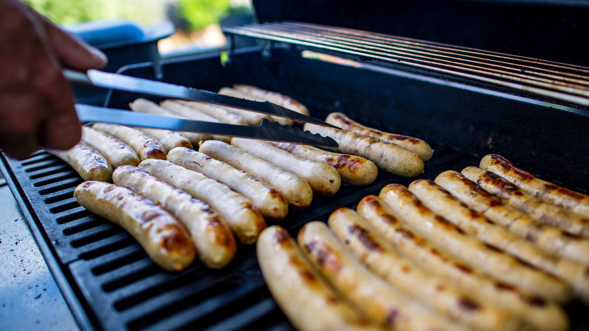 Ein Mann wendet Würstchen auf einem Grill: Einbrecher haben in Hagen Grillutensilien gestohlen und sofort genutzt. Ein Mann wendet Würstchen auf einem Grill: Einbrecher haben in Hagen Grillutensilien gestohlen und sofort genutzt.