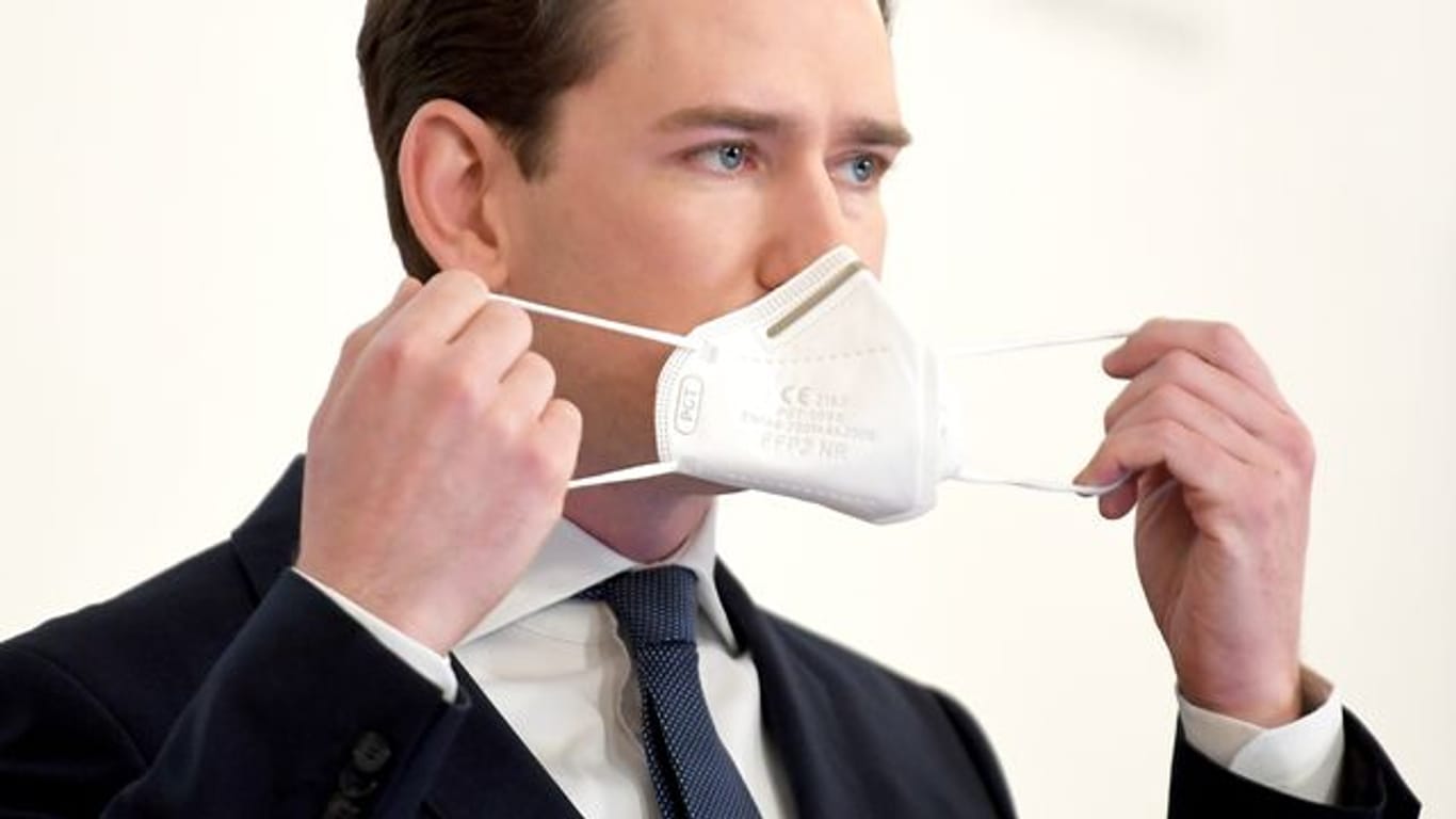 Sebastian Kurz (ÖVP), Bundeskanzler von Österreich, setzt bei einer Pressekonferenz seine Mund-Nasen-Bedeckung auf.