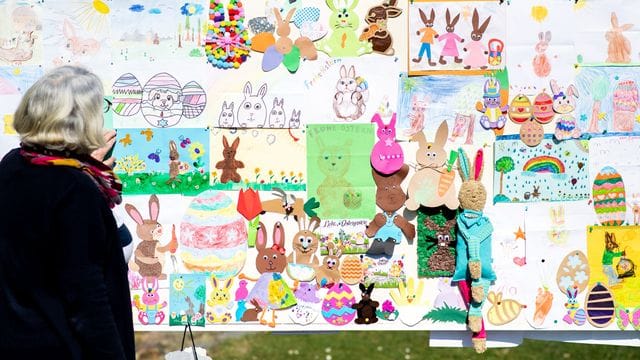 Doris Kröger, Mitarbeiterin im Osterpostamt, steht am Gemeindehaus vor einer Stellwand mit zahlreichen Briefen, die Kinder für den Osterhasen Hanni Hase geschrieben haben.