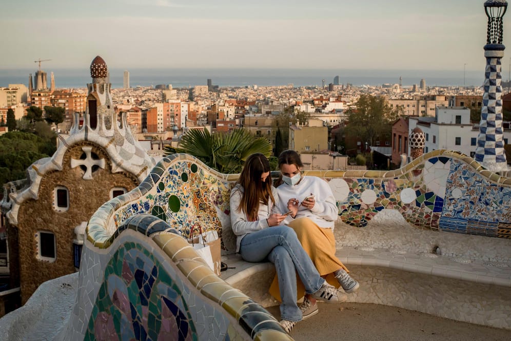 Barcelona: Zwei Mädchen sitzen auf einer Bank und tragen Masken. Die Stadt war zwischenzeitlich besonders von der Pandemie getroffen.