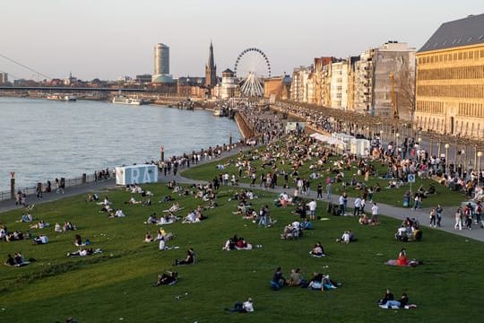 Menschen halten sich an der Rheinuferpromenade und den Rheinwiesen in Düsseldorf auf.