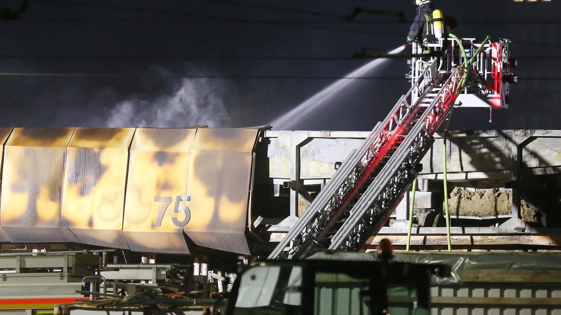 Ein Feuerwehrmann löscht von einer Drehleiter aus Glutnester auf dem Dach der Halle: Gegen 1 Uhr gingen mehrere Notrufe bei der Feuerwehr ein.