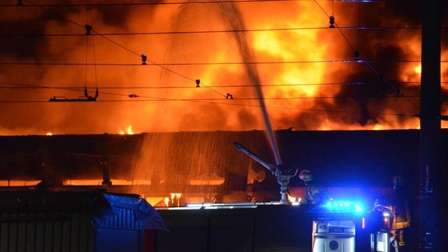 Von einem Feuerwehrfahrzeug aus löscht die Feuerwehr die Abstellhalle der Rheinbahn: Ein Übergreifen der Flammen auf das Straßenbahn-Depot konnte verhindert werden.