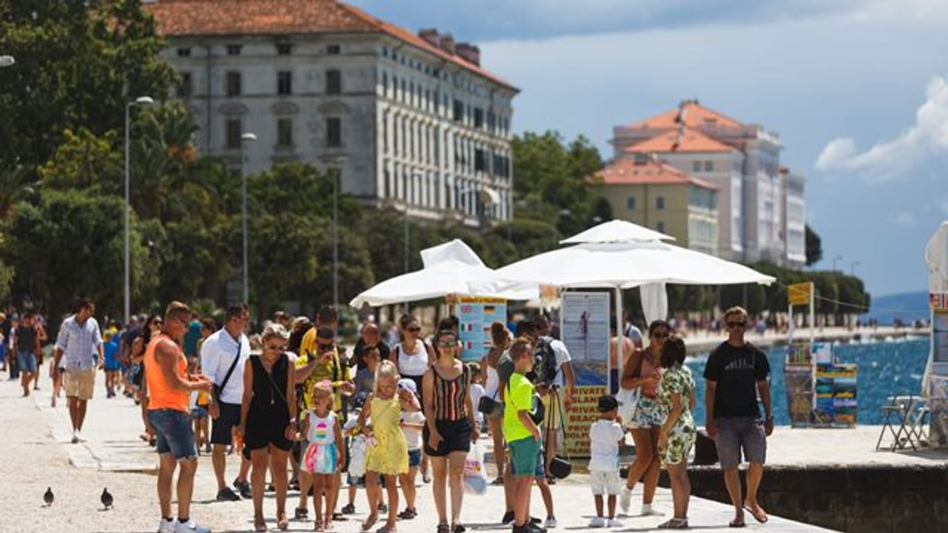 Touristen spazieren an der Uferpromenade in Zadar entlang.