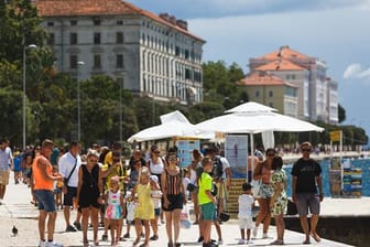 Touristen spazieren an der Uferpromenade in Zadar entlang.