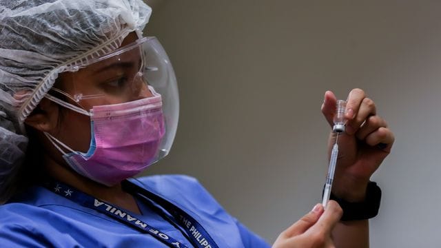 Eine medizinische Mitarbeiterin bereitet auf den Philippinen eine Impfung vor. Eine medizinische Mitarbeiterin bereitet auf den Philippinen eine Impfung vor.