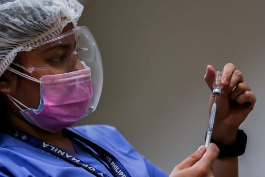 Eine medizinische Mitarbeiterin bereitet auf den Philippinen eine Impfung vor.