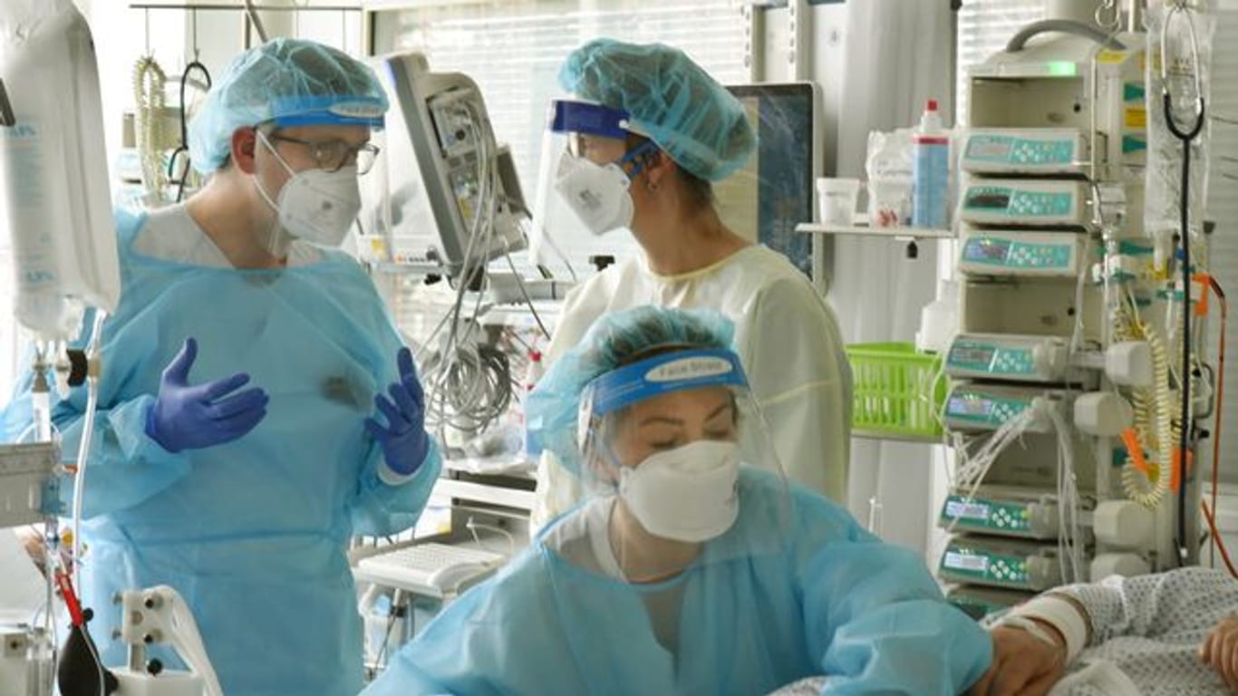 Mediziner stehen bei einem Patienten in der Covid-19-Station (Symbolbild): Die Uniklinik Leipzig muss Patienten aus Corona-Hotspots in Südsachsen aufnehmen.