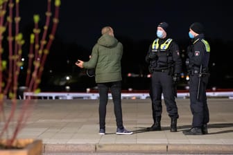 Die Polizei kontrolliert einen Mann: In vielen deutschen Städten und Regionen gelten nächtliche Ausgangsbeschränkungen.