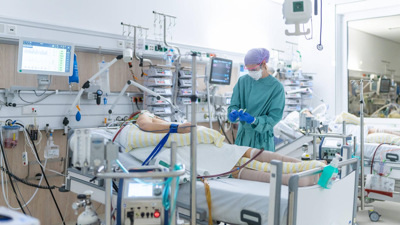 Ein Pfleger auf einer Corona-Intensivstation steht am Bett eines Patienten. Die Corona-Neuinfektionen steigen weiter.