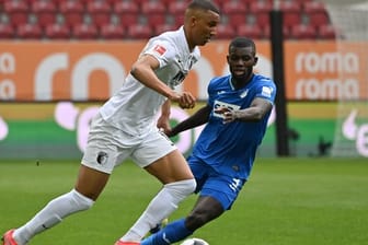 Augsburgs Abwehrspieler Felix Uduokhai (l) behauptet sich gegen Hoffenheims Stürmer Ihlas Bebou.