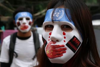 Junge Demonstranten in Yangon tragen Masken, auf denen das Logo der Vereinten Nationen, eine rote Hand über dem Mund, rote Tränen und Aufkleber mit der Aufschrift "Save Myanmar" zu sehen sind.