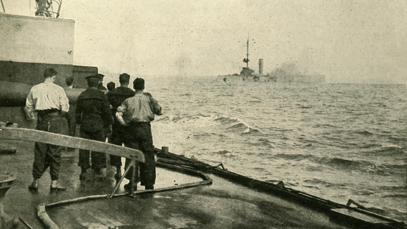 Das deutsche Kriegsschiff "SMS Mainz" (im Hintergrund) versinkt im Sommer 1914: Nun wollen Forscher herausfinden, wie gefährlich die sich zersetzenden Weltkriegswaffen für die Umwelt sind.