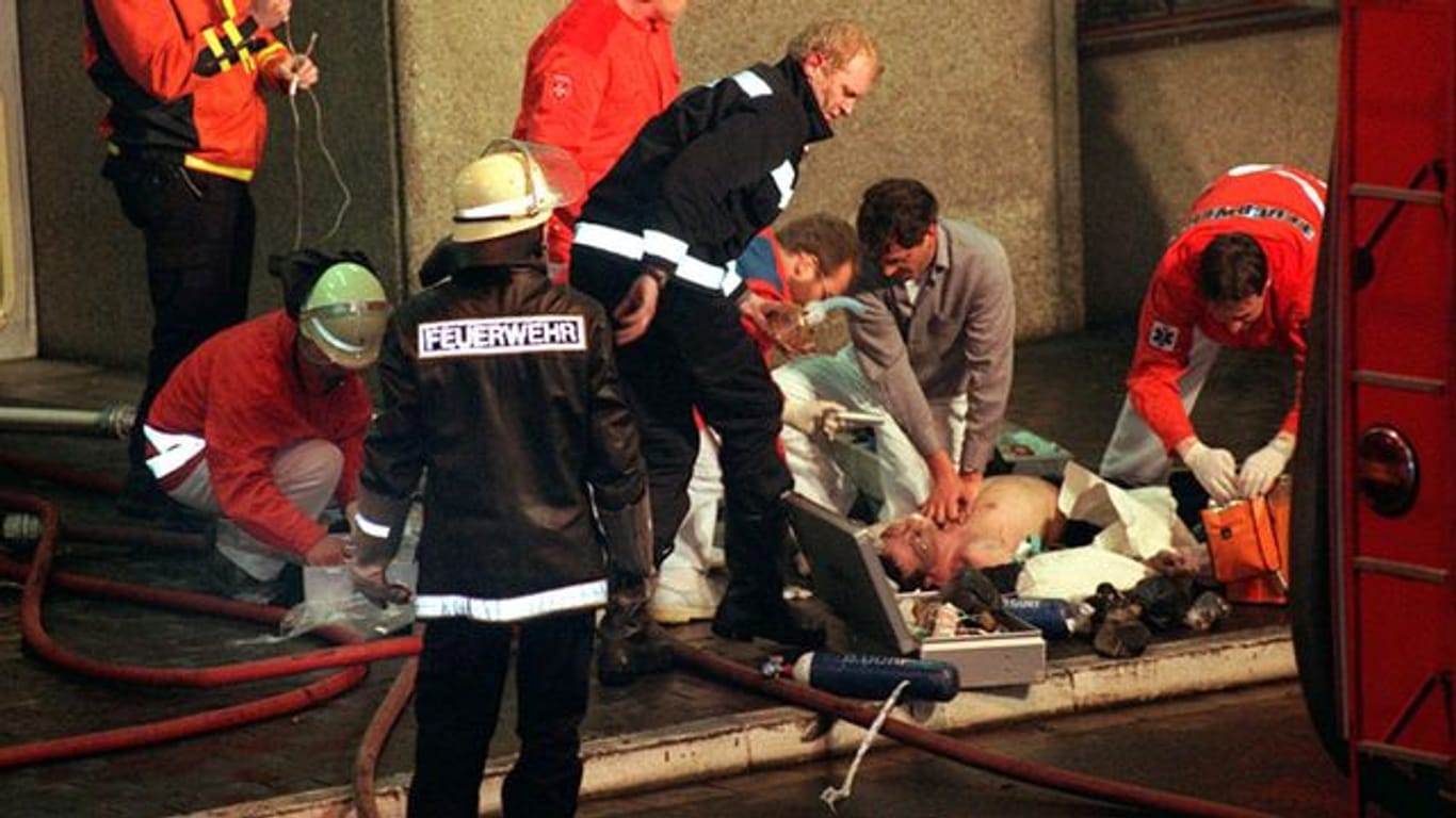 Das Bild vom 11. April 1996 zeigt Notärzte und Feuerwehrleute bei der Reanimation eines Verletzten nach dem Brand im Düsseldorfer Flughafen (Archivbild).